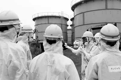 日前，日本核监管机构工作人员身穿保护服头戴面具，检查福岛第一核电站污水储藏罐。(图片来源：中新网)