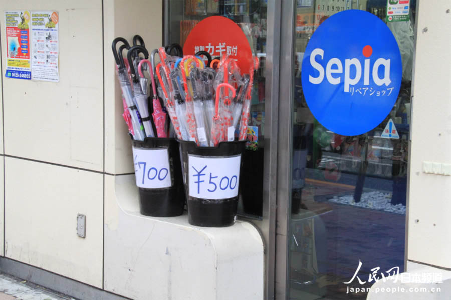 16日，车站外的小商店，店主把雨伞摆在最显眼的地方。