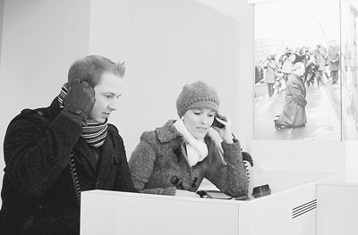 　班内特（左）和朋友在观看勃兰特生平资料，他们身旁就是勃兰特华沙之跪的照片。