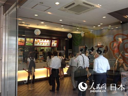 23日，东京都内一家麦当劳餐厅内，不少客人在排队购买餐食。