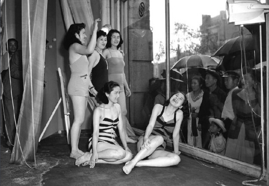 　1950年6月5日，東京一家百貨商店為了吸引路人的注意，在櫥窗裡用活人模特進行泳衣展示。雖然當時雨水傾斜，卻仍舊沒有澆滅人們的好奇心。
