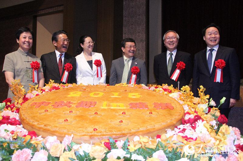 出席開幕式的中日雙方代表共同揭開特別訂制的大型月餅