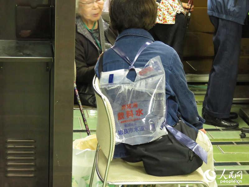 4月22日，熊本市中央區役所內，一名女性背著飲用水排隊等待辦理手續