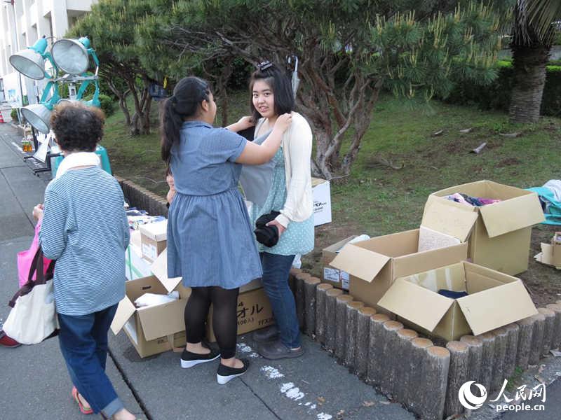 4月22日，益城町的兩名避難民眾在捐助的物品中挑選衣物