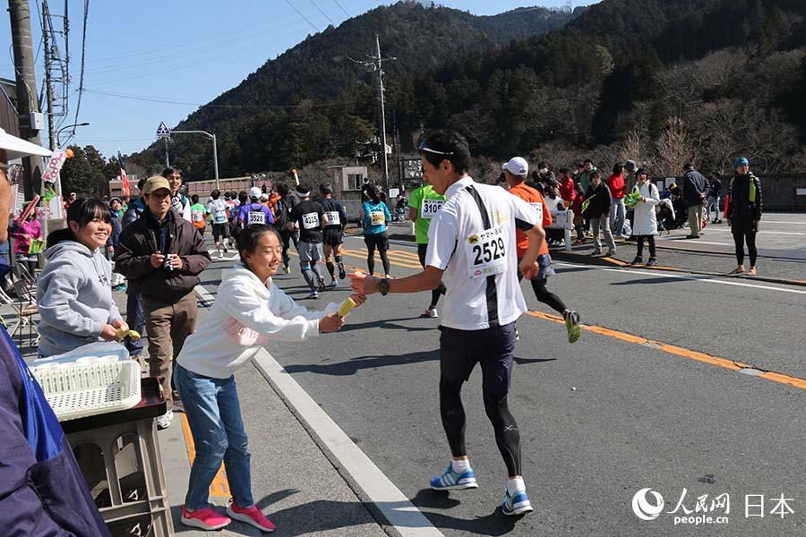 17日，日本青梅市熱心市民在30公裡賽程為參賽者送上補給品。