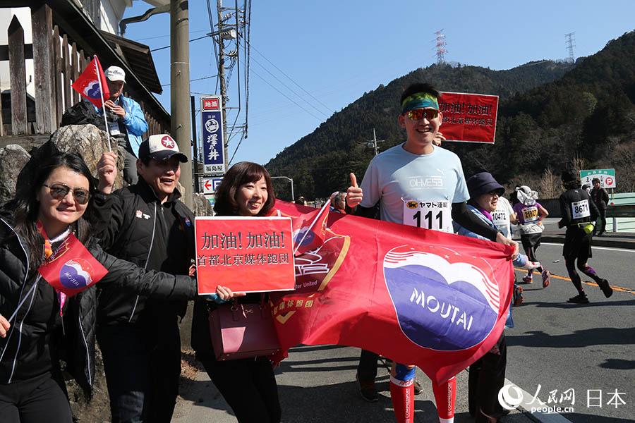 17日， 人民網參賽跑者鄭紫豪手持貴州茅台橫幅，與助威團隊在30公裡賽程合影。