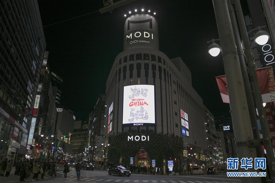 2月10日，在日本東京，澀谷街頭的一個商場大樓的顯示屏上打出多種語言組合出的中文“加油”字樣。新華社記者 杜瀟逸 攝