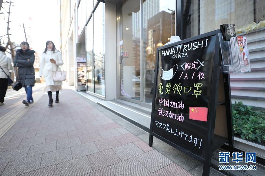 2月11日，在日本東京，銀座的一個商鋪門前的招牌上寫著免費贈送口罩和為中國武漢加油鼓勁的內容。新華社記者 杜瀟逸 攝