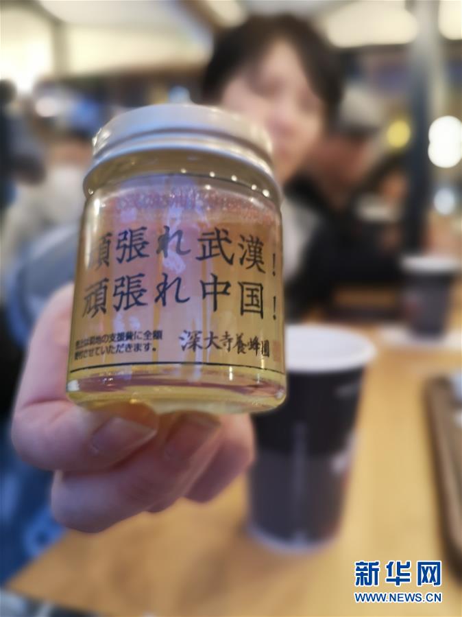 2月8日，在日本東京池袋的元宵節慶祝活動現場，市民展示“為中國武漢加油攤位”上的蜂蜜。蜂蜜的包裝上寫著“武漢加油！中國加油！”。該攤位為中國抗擊新冠肺炎疫情向人們募捐，並將銷售蜂蜜所得全部捐出。新華社發（黃檗文化促進會供圖）
