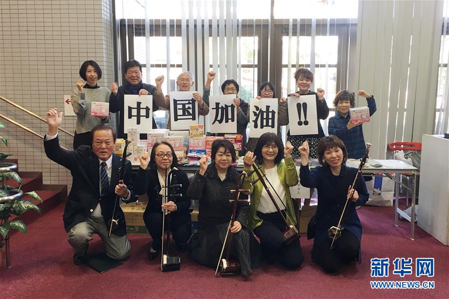 2月9日，在日本名古屋，張濱二胡學院的日本學員舉著“中國加油”的標語和他們向中國捐贈的口罩一起合影。新華社發（谷優惠 攝）