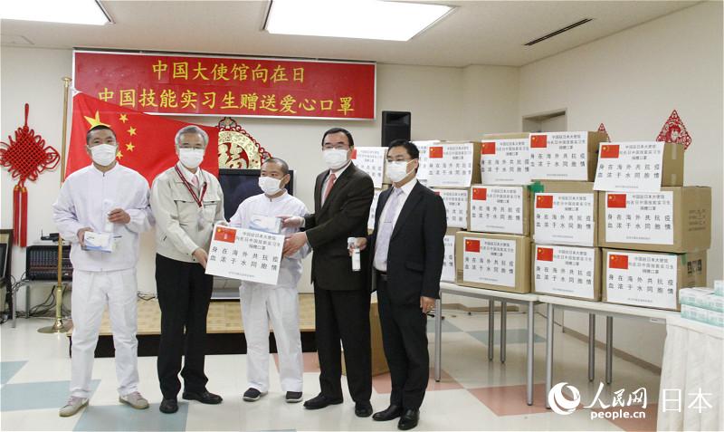 中国驻日本大使馆经济商务公使宋耀明(左二)向中国技能实习生代表赠送爱心口罩