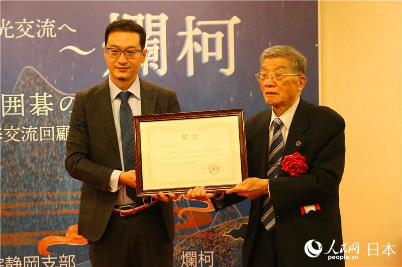 中國駐日本大使館文化處一等秘書蘇濤向40年來致力於中日友好交流的靜岡圍棋支部聯合會名譽會長八木勇頒發表彰証書。（李沐航 攝）
