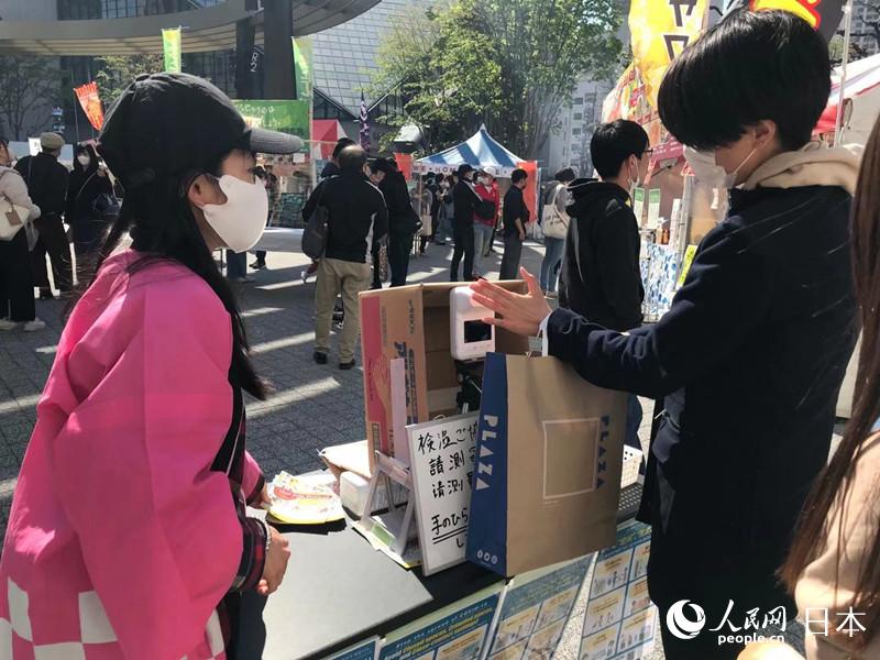 日本民眾在監測體溫、接受消毒后依次進入活動現場。（李沐航 攝）
