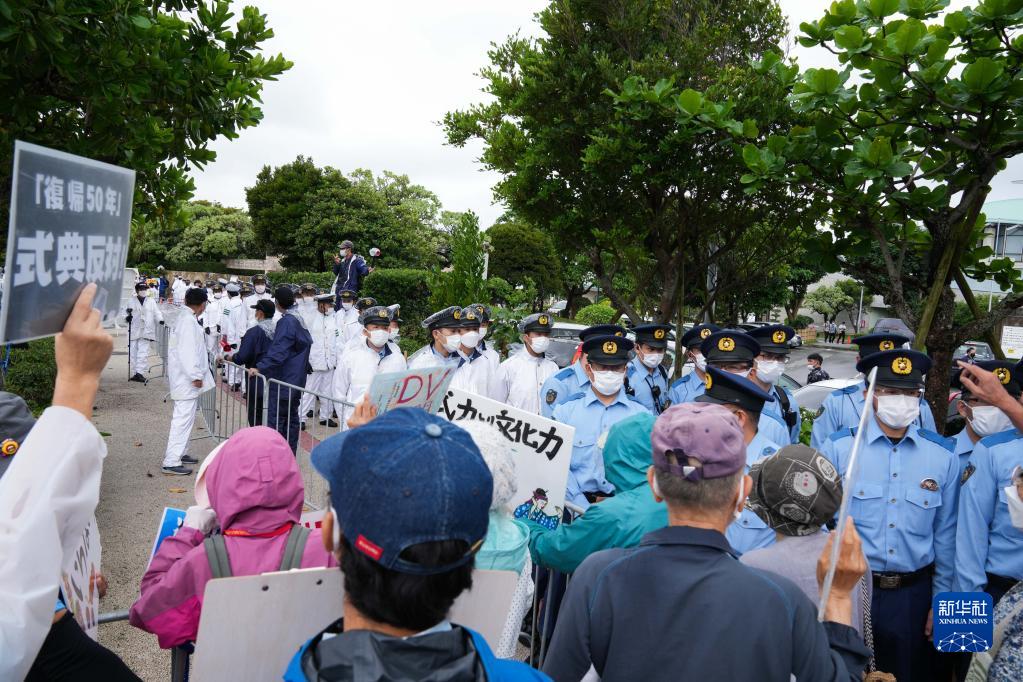 5月15日，在日本沖繩，警察在沖繩回歸日本本土50周年紀念儀式現場外阻攔抗議者。新華社記者 張笑宇 攝