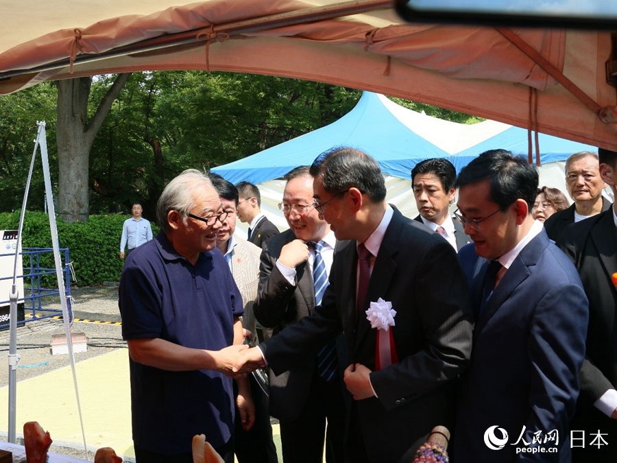 中国驻日本大使吴江浩在山东省委宣传部副部长、省电影局局长程守田的随同下，与微刻艺术家张翼进行疏通。东谈主民网 许可摄