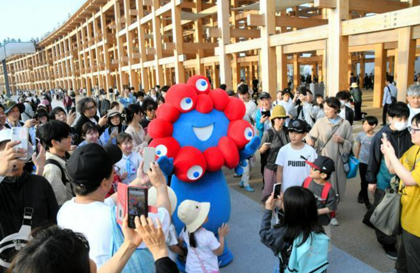 图片：大阪世博会的官方吉祥物“脉脉”(MYAKU-MYAKU)“脉脉”吸引了大量观众围观。（图片来源：《朝日新闻》）