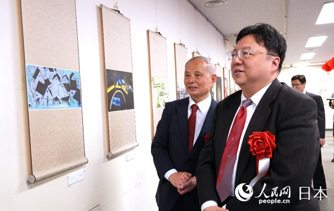 主办方代表冯学敏（左）向陈巍总领事（右）介绍展出作品。人民网 许可摄