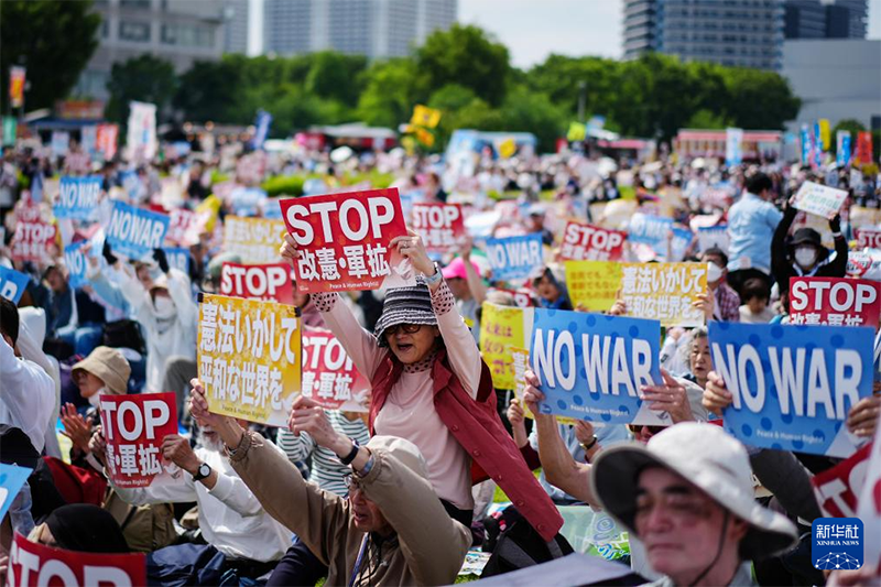  5月3日，在日本东京有明防灾公园，民众手持标语参加集会。新华社记者 贾浩成 摄