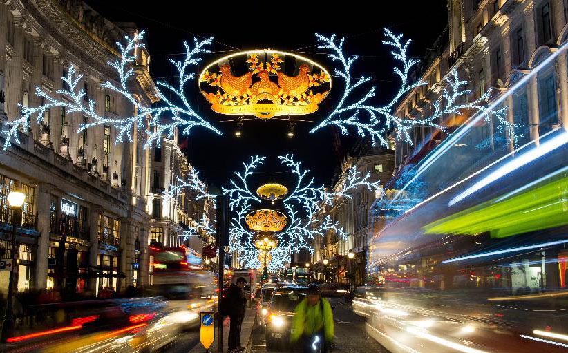 12月14日，在英国伦敦，行人和车辆经过街头的圣诞装饰。