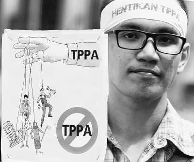 19日，一位吉隆坡当地民众举着拒绝TPP协定的宣传画报。