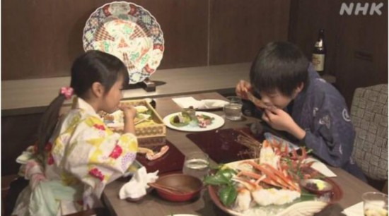 金泽市的一家四口得到免费品尝价值500万日元帝王蟹的机会。图为两个孩子正在食用帝王蟹。。图片来源：日本放送协会(NHK)报道截图。