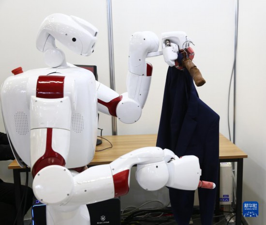 11月30日，在日本東京舉辦的日本國際機器人展上，早稻田大學的機器人展示往衣架上挂衣服。新華社記者 錢錚 攝